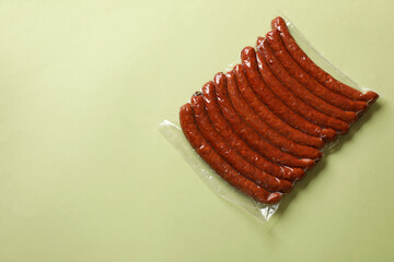 Wall Mural - Pack of smoked sausages on green background, top view. Space for text