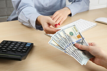 Wall Mural - Client giving dollar banknotes to cashier at table in money exchange, closeup