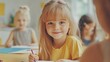 © BerkahStock - Happy preschool girl drawing at table with classmates in background.