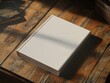 © kribbox - Blank book mockup on wooden table with plants and sunlight
