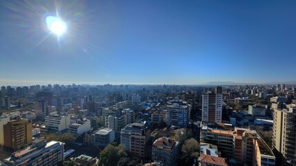 Wall Mural - Panoramic cityscape view showcasing urban architecture under a bright sun with clear blue skies and distant mountains