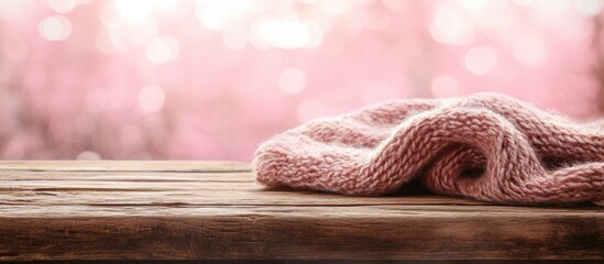 Wall Mural - Rustic wooden table with soft pink bokeh background creating a warm and cozy atmosphere for textile or home decor imagery.