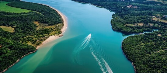 Canvas Print - Aerial view of a river merging with the sea showcasing vibrant water textures and lush green surroundings in a serene landscape.