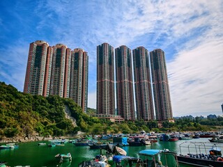 Poster - Hong Kong apartments in Tseung Kwan O rise above the harbor. Houses are nestled on green hillsides near the waterfront.