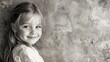 © aleks - Child with long hair smiles warmly against a textured wall in black and white capturing a moment of joy and innocence