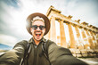 © Davide Angelini - Happy tourist visiting the Acropolis of Athens, Greece - Smiling traveler man taking selfie picture with smart mobile phone outdoors