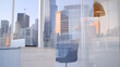 © bcendet - Office interior view looking out on city skyscrapers, desk, chair & lamp. Empty workstation with blurred buildings as background