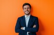 © Lady O - Portrait of a successful smiling young business man dressed in a suit. Studio shot against a vivid orange background.