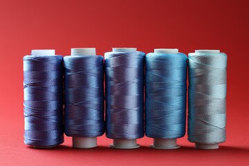 Wall Mural - Spools of colorful sewing threads on red background