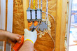 © ungvar - Contractor with spray foam insulation electrician connects wires to junction boxes inside wooden structure during construction.