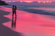 © imager - couple on the beach in pinkish background sun merging in clouds, holding each other in romantically mood in a silhouette background.