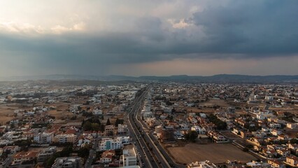 Canvas Print - Aerial view of urban landscape with highway and clouds.