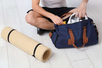 Wall Mural - Young man with sports bag and yoga mat in gym