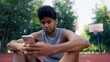 © Synthex - Young man uses his phone after a basketball game, monitoring his fitness activity and stats