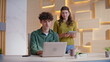 © stockbusters - Woman boss showing tablet to man working at laptop in creative agency office.