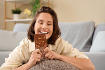 Poster - Beautiful young happy woman with tasty chocolate bar at home