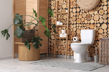 Wall Mural - Interior of restroom with toilet bowl, ladder, houseplant and folding screen near wooden wall