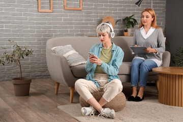 Wall Mural - Teenage girl with headphones using mobile phone at psychologist's office