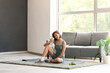 © Pixel-Shot - Beautiful young woman with sports bottle on yoga mat in living room