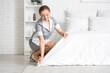 © Pixel-Shot - Young chambermaid making bed in room