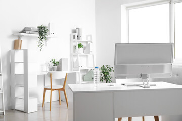 Wall Mural - Bottle of water and computer on desk in light office