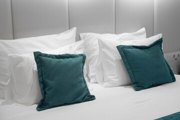 White and green pillows in room. Bedroom in hotel