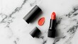 © วรรณภา มะโนศรี - Open lipstick and matching nail polish bottle, bright coral color, lying on a marble surface, vibrant and trendy