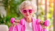 © weerasak - A cheerful elderly woman wearing pink sunglasses lifts pink dumbbells, showcasing an active and vibrant lifestyle.