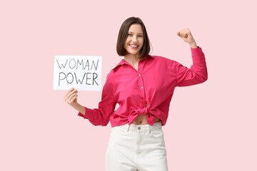beautiful young woman holding woman power sign and showing muscles on pink background. women's histo