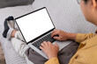 © jojo - Man using laptop with white screen mockup on sofa