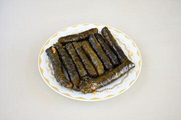 Wall Mural - Delicious dolma (sarma) stuffed grape leaves rice, white yogurt sauce. Lebanese dolma sarma on plate. Lebanon turkish greek middle eastern cuisine. (Turkish name; yogurtlu yaprak sarma)