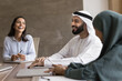© fizkes - Group of professionals engaged in positive, collaborative meeting. Arabian businessman dressed in traditional attire lead negotiations with shareholders, clients or investors. Deal, success, business