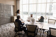 © fizkes - In boardroom group of intercultural businesspeople discussing various business-related topics, share strategy, planning cooperation sit at table in skyscraper office. Negotiations between shareholders