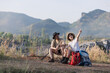 © kamonrat - A couple takes a break during their hike, sitting on a trail with a scenic mountain view.