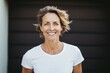 © Vorda Berge - Smiling happy middle aged Caucasian woman wearing a white t shirt outside