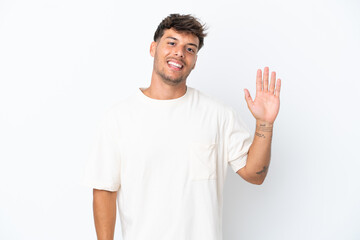 Sticker - Young caucasian handsome man isolated on white background saluting with hand with happy expression