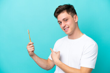 Wall Mural - Young Brazilian man brushing teeth isolated on blue background pointing back