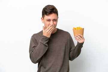 Wall Mural - Young Brazilian man holding fried chips isolated on white background happy and smiling covering mouth with hand