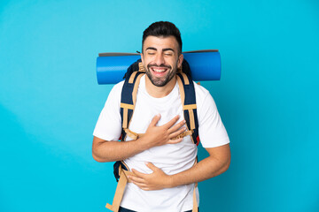 Wall Mural - Young mountaineer man over isolated blue background smiling a lot