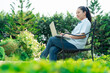 © bixpicture - Woman working remotely on laptop in green park. Woman work-from-home flexibility, freelancing and balanced lifestyle with digital productivity in relaxing and refreshing natural environment.