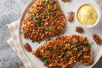 Wall Mural - Baked Pecan Crusted Chicken breast with Honey Mustard Sauce close-up in a plate on the table. Horizontal top view from above