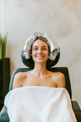 Sticker - A woman is sitting in a chair with a towel wrapped around her head