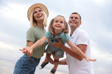 Wall Mural - Happy family spending time together near sea on sunny summer day