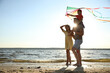 © New Africa - Happy parents and their child playing with kite on beach near sea. Spending time in nature