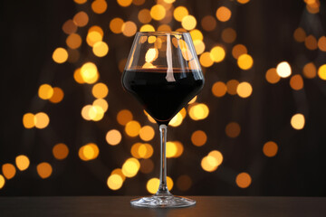 Wall Mural - Tasty red wine in glass on table against dark background with blurred lights, bokeh effect