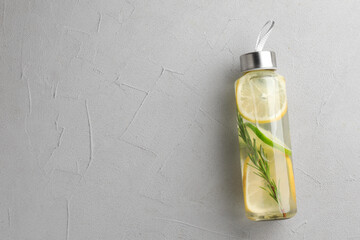 Wall Mural - Lemon water with lime and rosemary in bottle on grey table, top view. Space for text