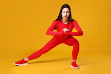 Wall Mural - Woman in sportswear exercising on orange background