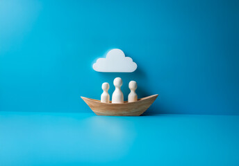 Aufkleber - Three wooden figures in a small wooden boat are positioned below a white cloud against a vivid blue backdrop. A simple, minimal, and conceptual composition.