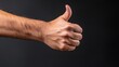 © Yevheniia - Close-up of a caucasian male adult thumb gesture against a dark background