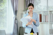 © Witoon - Tired Asian businesswoman sitting at desk working, pile of documents and looming deadline. Stress and fatigue visible on her face as she works on laptop.